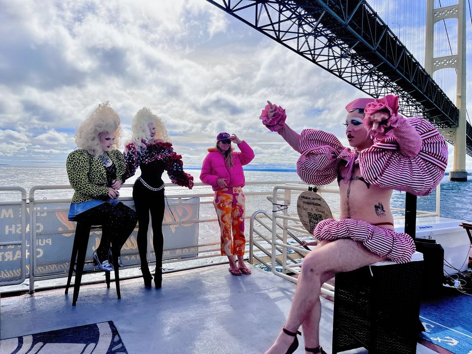 Drag-előadók egy hajó fedélzetén, háttérben a Mackinac híd