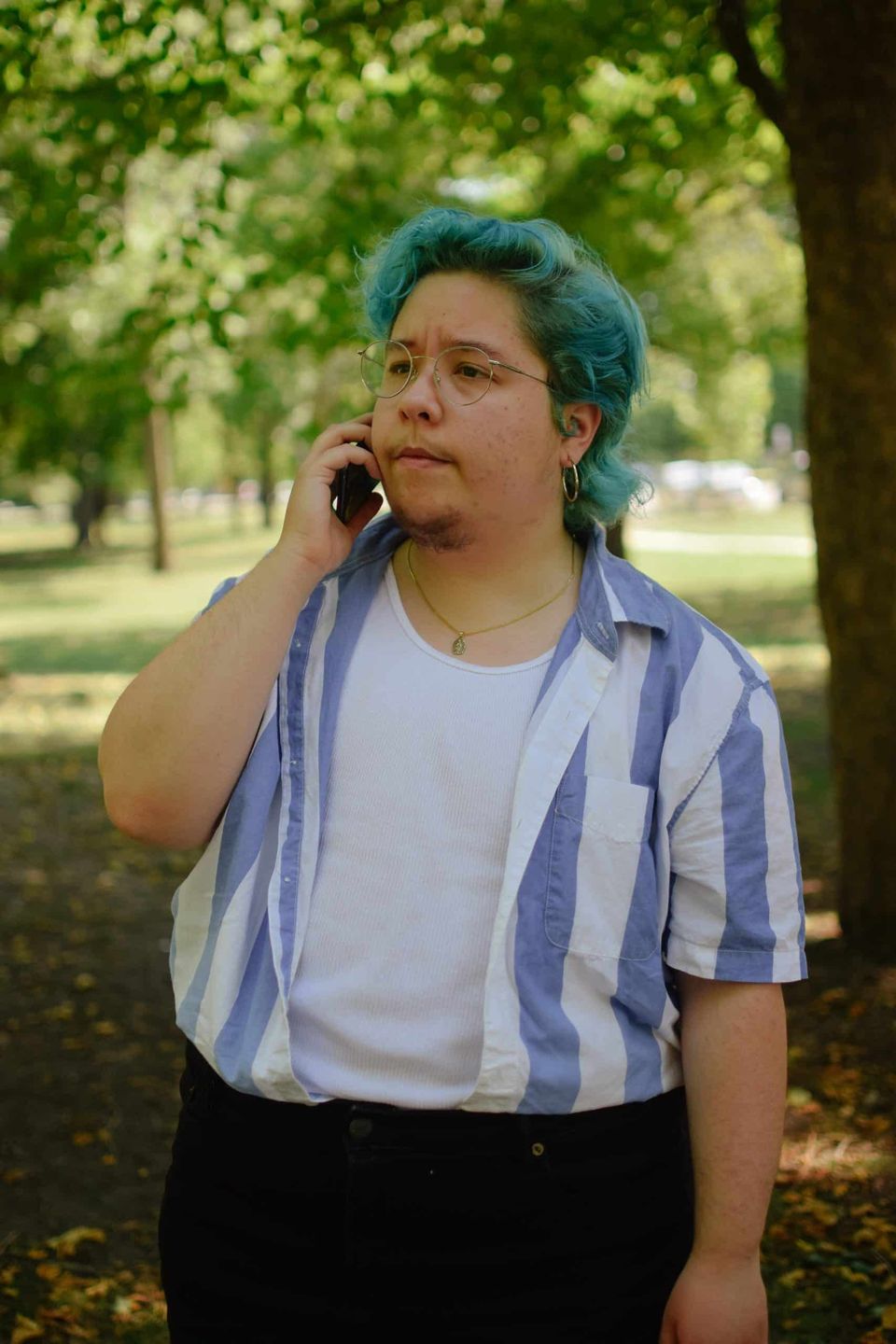 Csíkos inges ember telefonál a fák alatt
