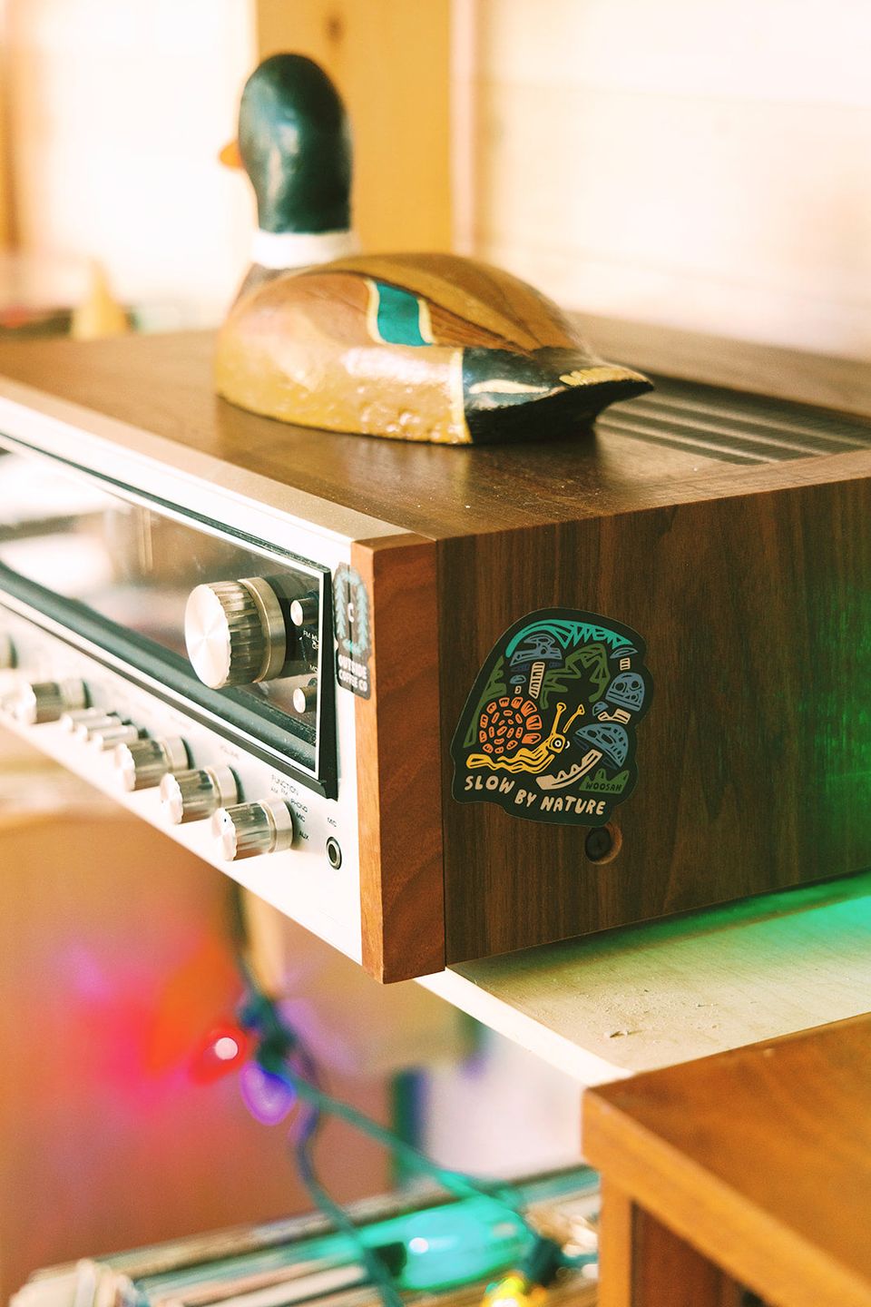 Snail sticker on a vintage stereo receiver topped with a carved duck