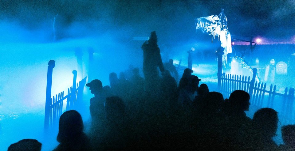 Haunted hayride riders in blue fog at night