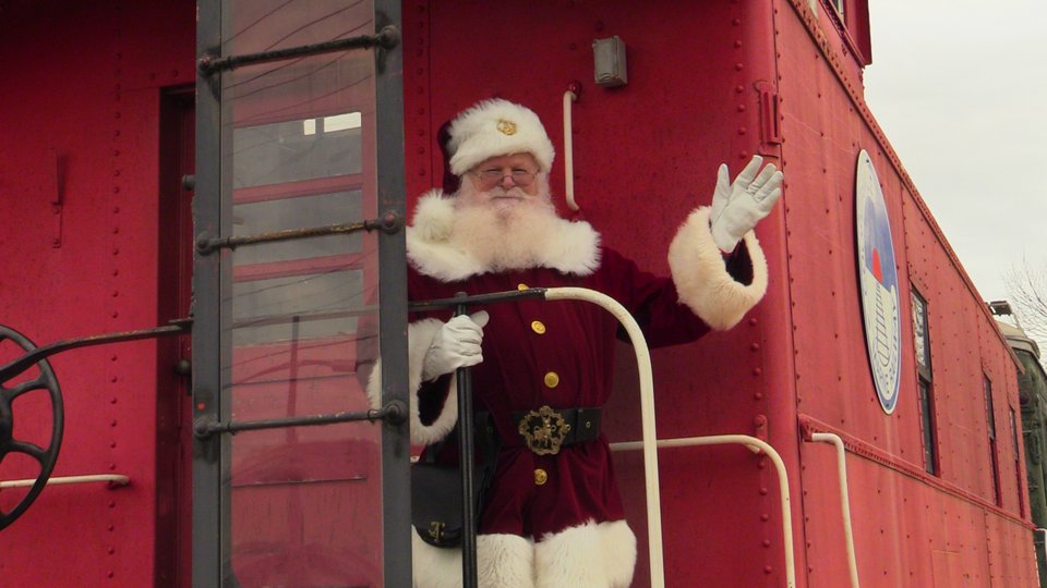Santa waving from the back platform of the red caboose