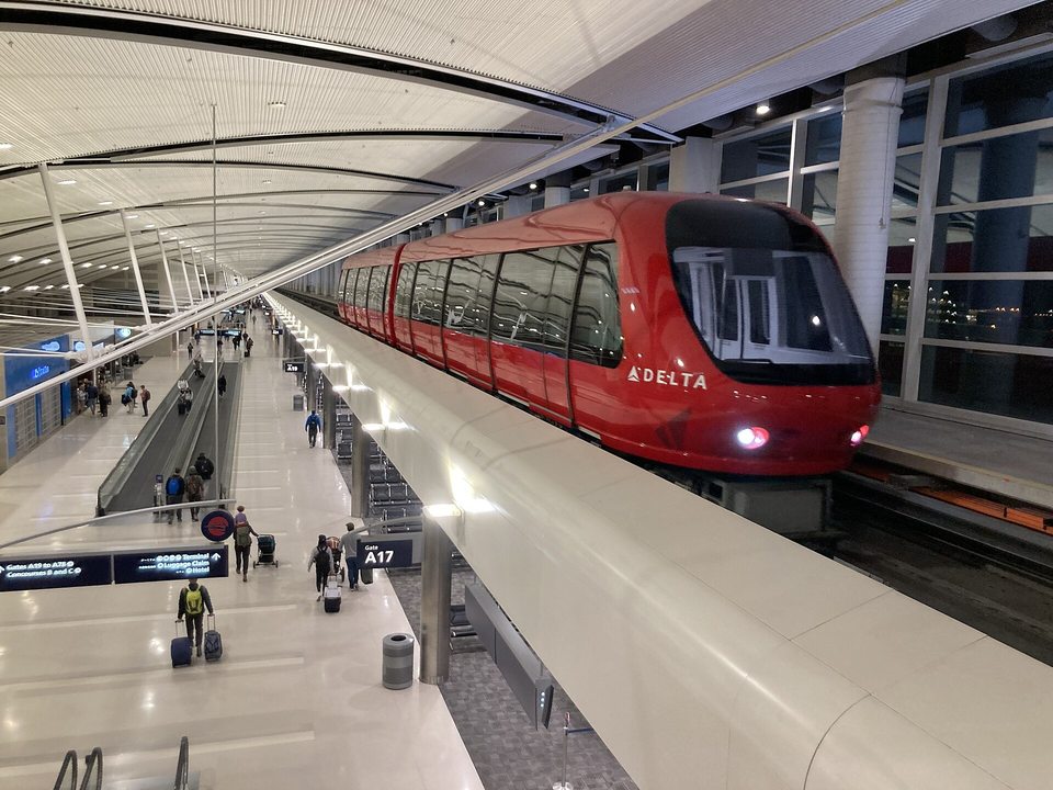 A piros ExpressTram beáll a megállójába az A csarnok magasított pályáján, a McNamara terminálban.