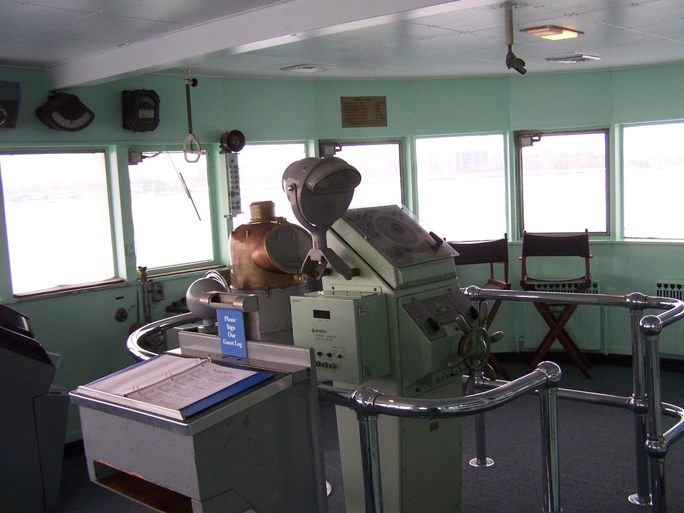 Inside the pilothouse, with engine telegraphs and windows facing the river