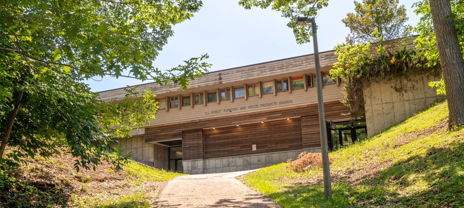 The wood-clad U. J. Noblet Forestry Building seen from the bottom of the hill in summer; the atrium is inside