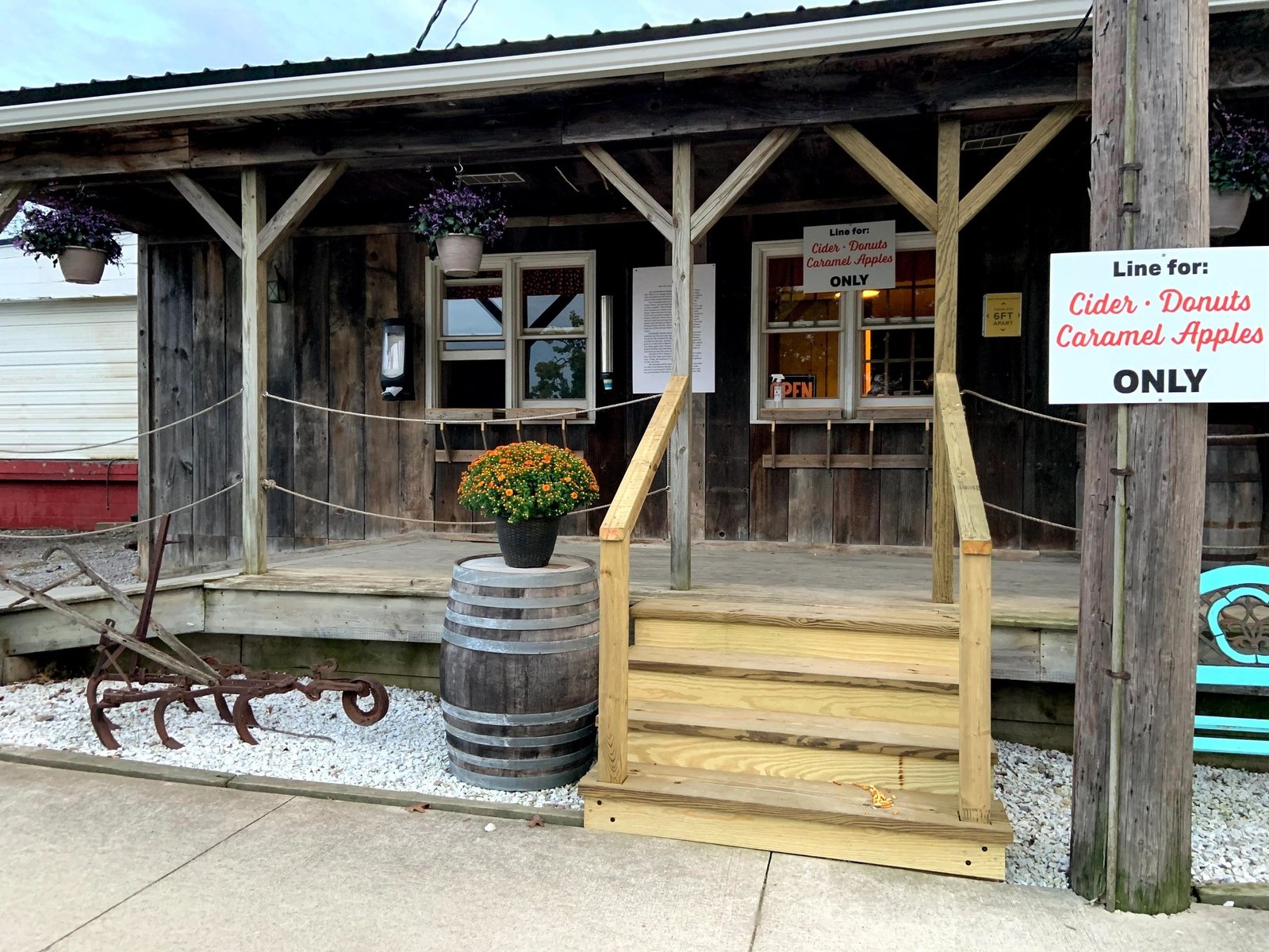 The wooden porch of Hy's Cider Mill store with a sign for the cider and donut line