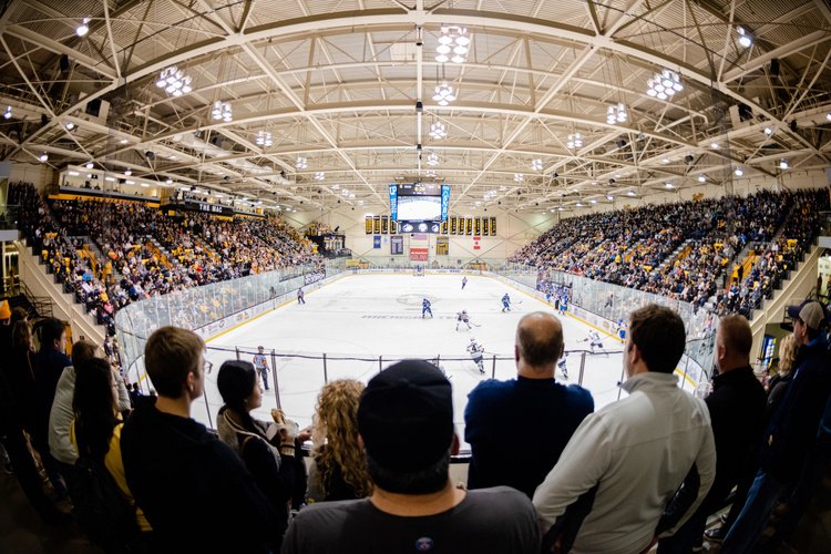 A hockey game at the MacInnes arena seen from the stands, video board hanging over center ice