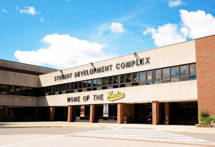 The Student Development Complex brick facade with its „Home of the Huskies” lettering under a blue sky
