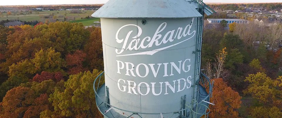 The water tower lettered Packard Proving Grounds above autumn trees
