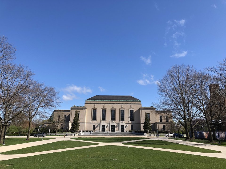 The Rackham Building across the lawn and walkways, bare trees around it, spring 2020
