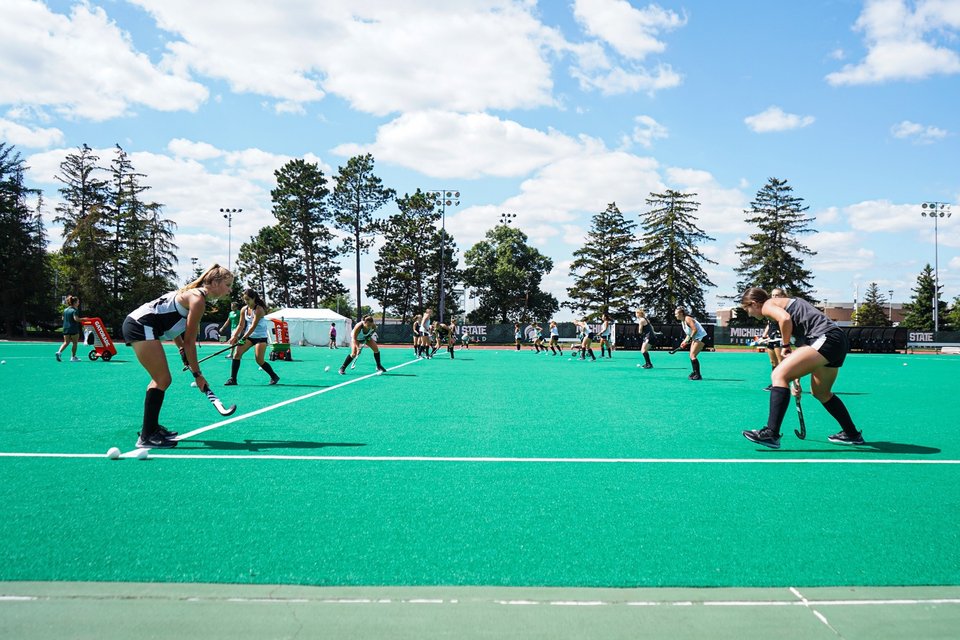 A field hockey game at Ralph Young Field, pine trees lining the field