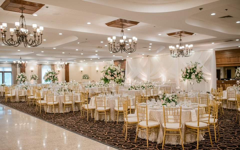 Ballroom set for a wedding with chandeliers and gold chairs