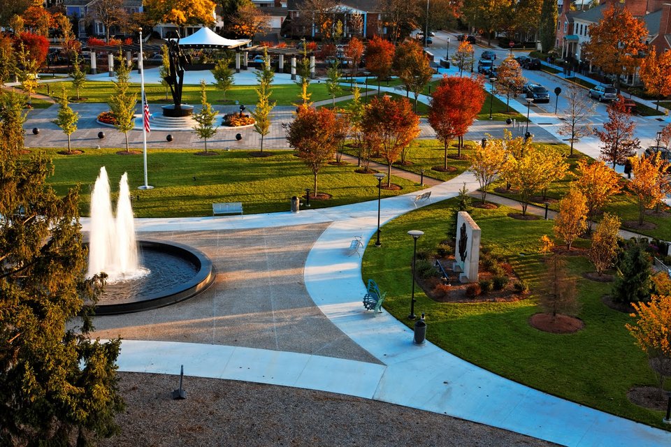 The park's fountain, curving paths and red autumn trees from above