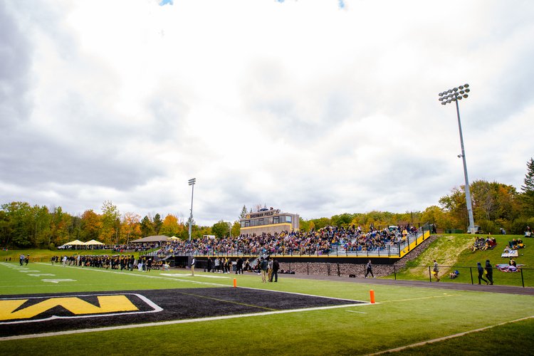 Game day at Sherman Field: full grandstand and light towers under a cloudy sky