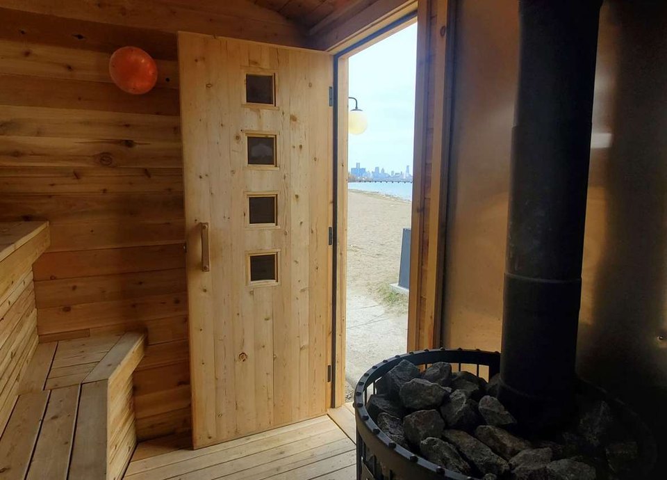 A szauna belseje a fatüzelésű kályhával; a nyitott ajtón át a strand és a detroiti belváros