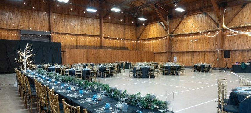 Wood-paneled hall with long banquet tables set for an event
