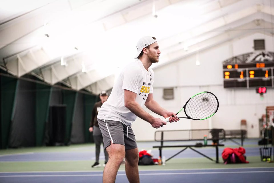 A Bronco player on an indoor court with the scoreboard in the background