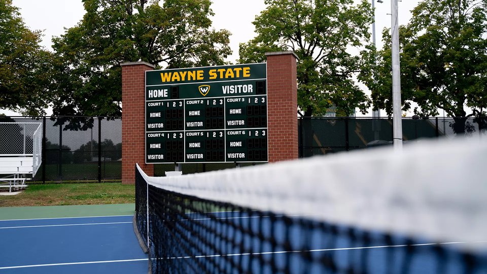 The brick-framed Wayne State tennis scoreboard behind the net