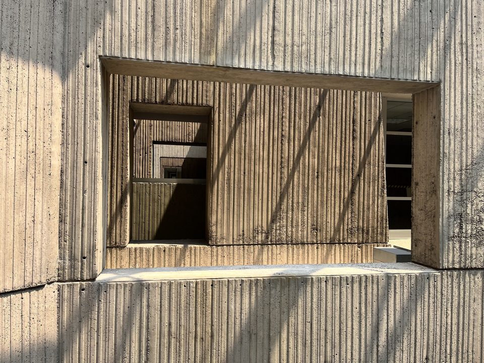 Ribbed raw-concrete wall with an opening inside the Renaissance Center (2023)