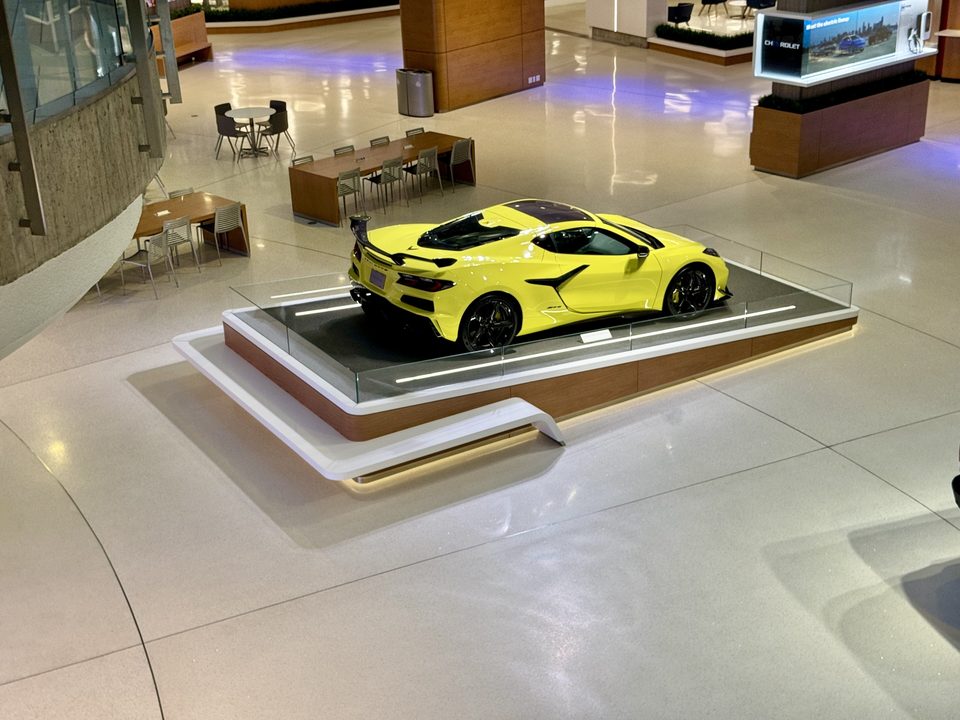 A yellow Corvette on a display platform in the atrium, 2024