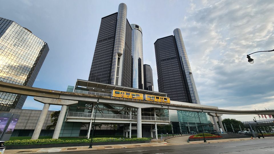 A yellow People Mover train in the Renaissance Center station, with the towers above (2025)