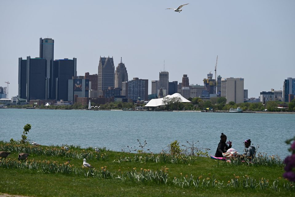 Picnickers on the Belle Isle shore in May 2023, with downtown across the water and the Renaissance Center on the left