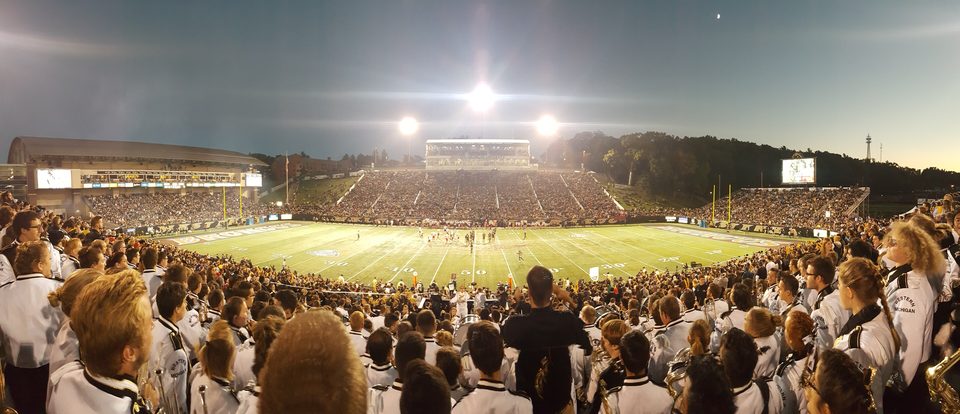 Panoráma a Waldo Stadium diákszektorából esti fényben, előtérben a zenekar tagjai