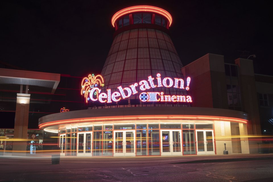 A Celebration! Cinema North kúp alakú tornya és íves, üvegajtós bejárata éjjel, neonfeliratokkal és az autók fénycsíkjaival