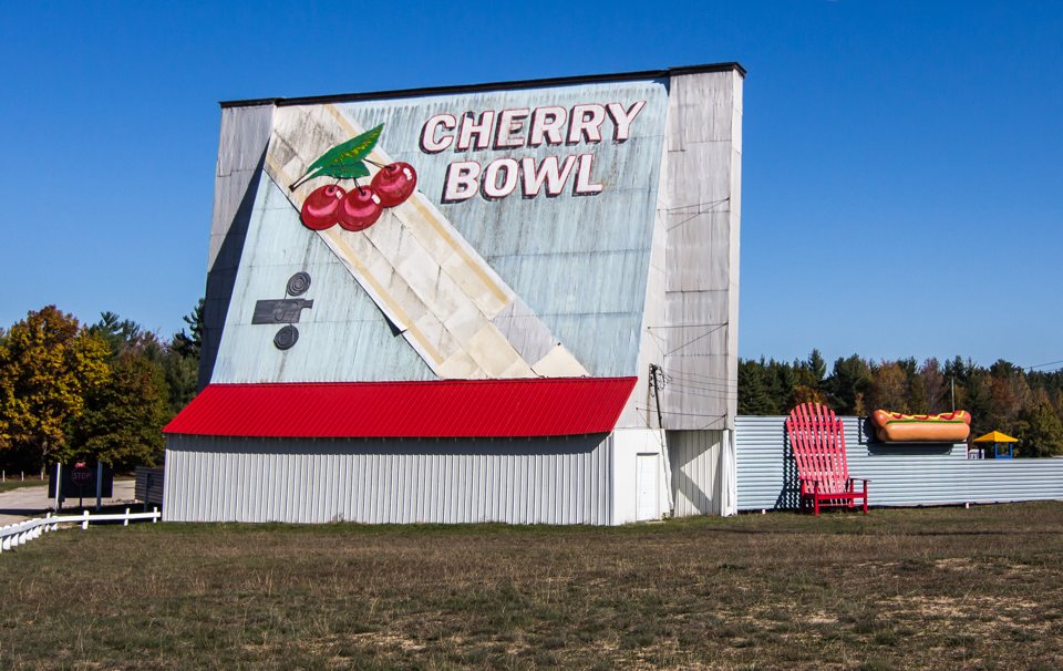 The Cherry Bowl Drive-In's painted screen tower with cherries and the CHERRY BOWL name, next to a giant red Adirondack chair and a hot dog sculpture