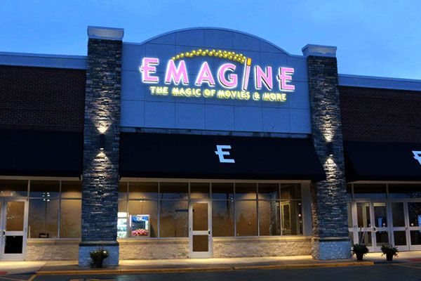 The Emagine Macomb entrance at dusk with its lit sign, stone pillars and black awnings