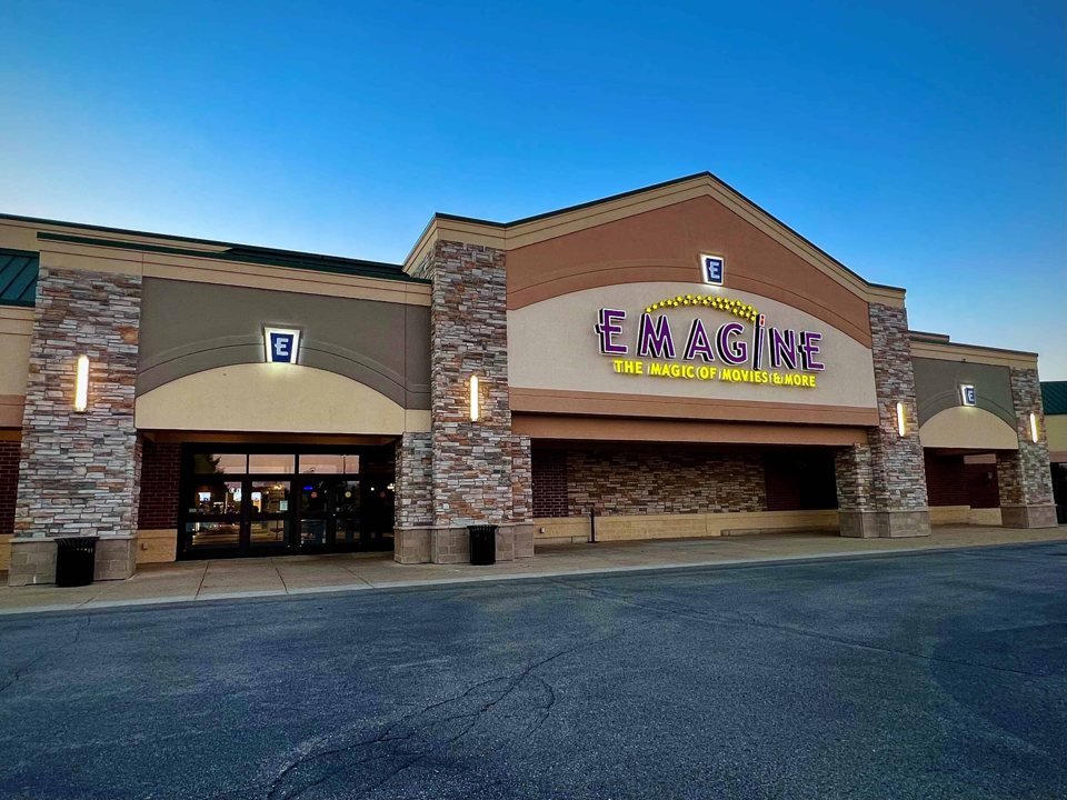 The stone-clad facade of Emagine Saline with its lit sign under a blue evening sky