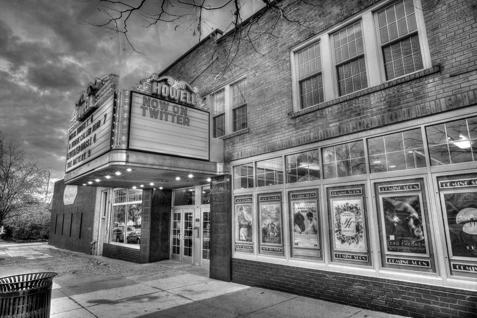 A Howell Theater márkiza és filmplakátokkal teli kirakatai fekete-fehér fotón, borús égbolt alatt