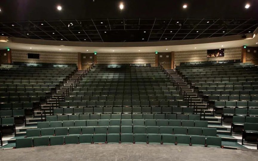 A Meadow Brook Theatre üres nézőtere zöld székekkel, a színpad széléről nézve
