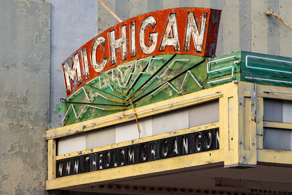 Close-up of the weathered red MICHIGAN neon sign and the green-trimmed marquee