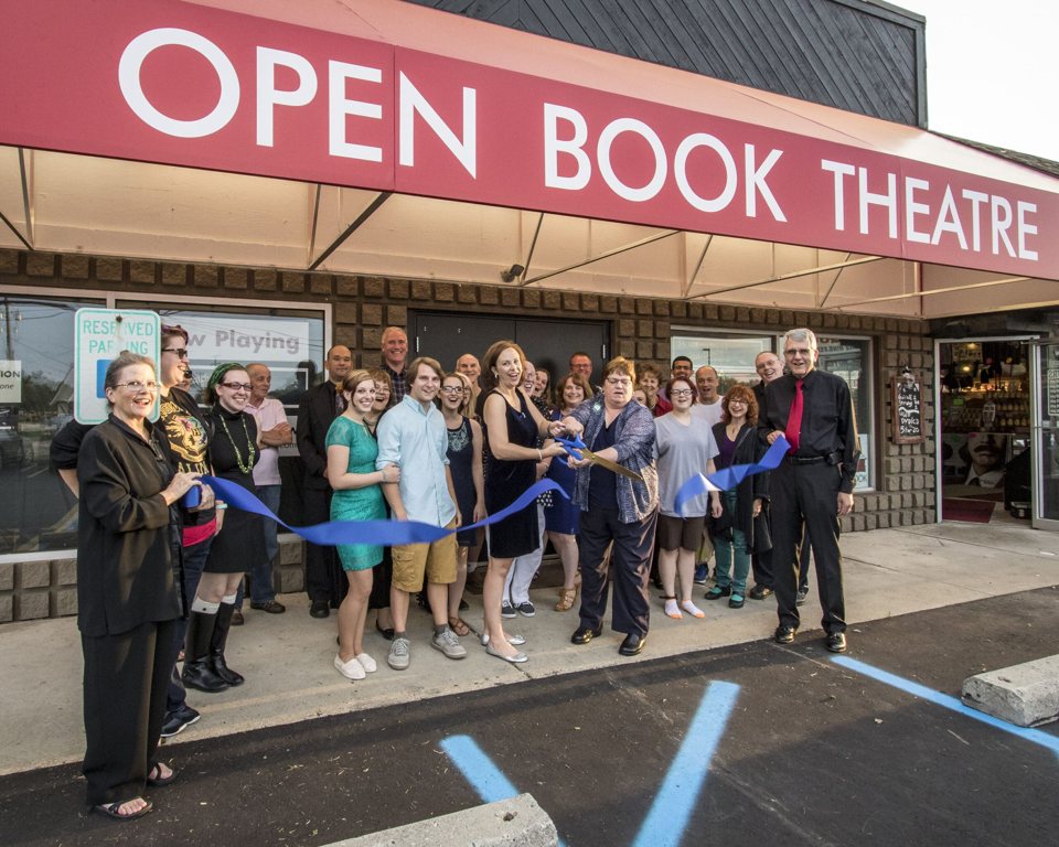 Szalagátvágás az Open Book Theatre piros előtetője alatt, a társulat tagjaival és támogatóival