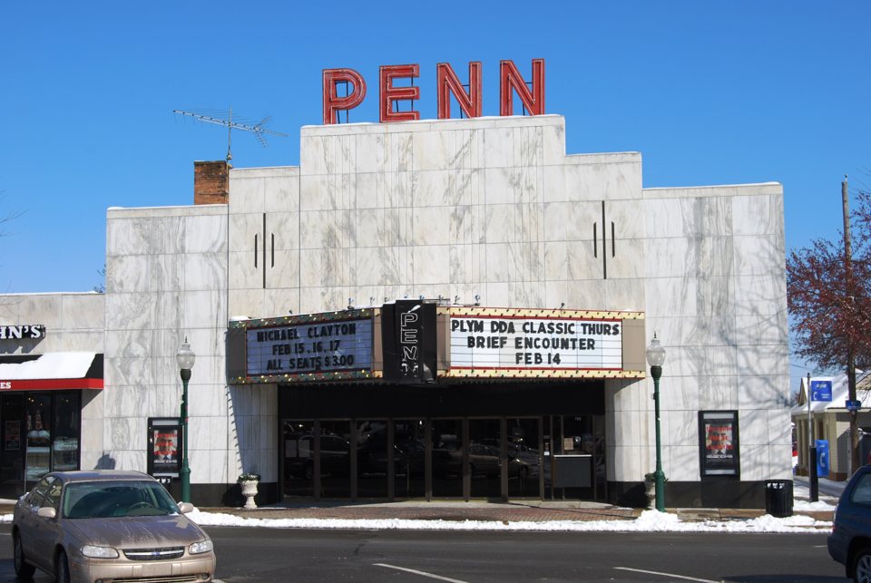 The Penn Theatre's white facade and marquee in sunshine under a blue sky