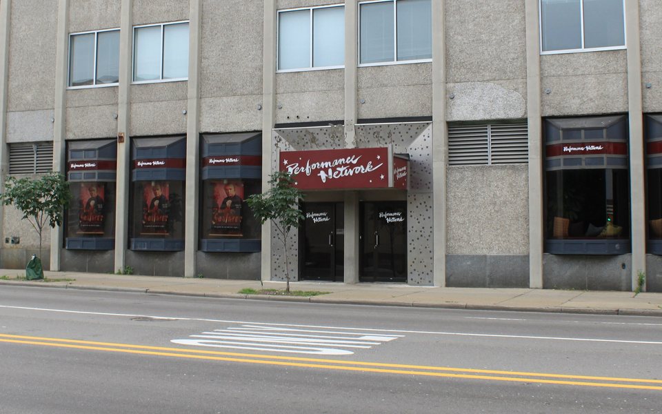 Performance Network's former entrance with its maroon sign and poster-filled windows on the ground floor of a Fourth Avenue office building