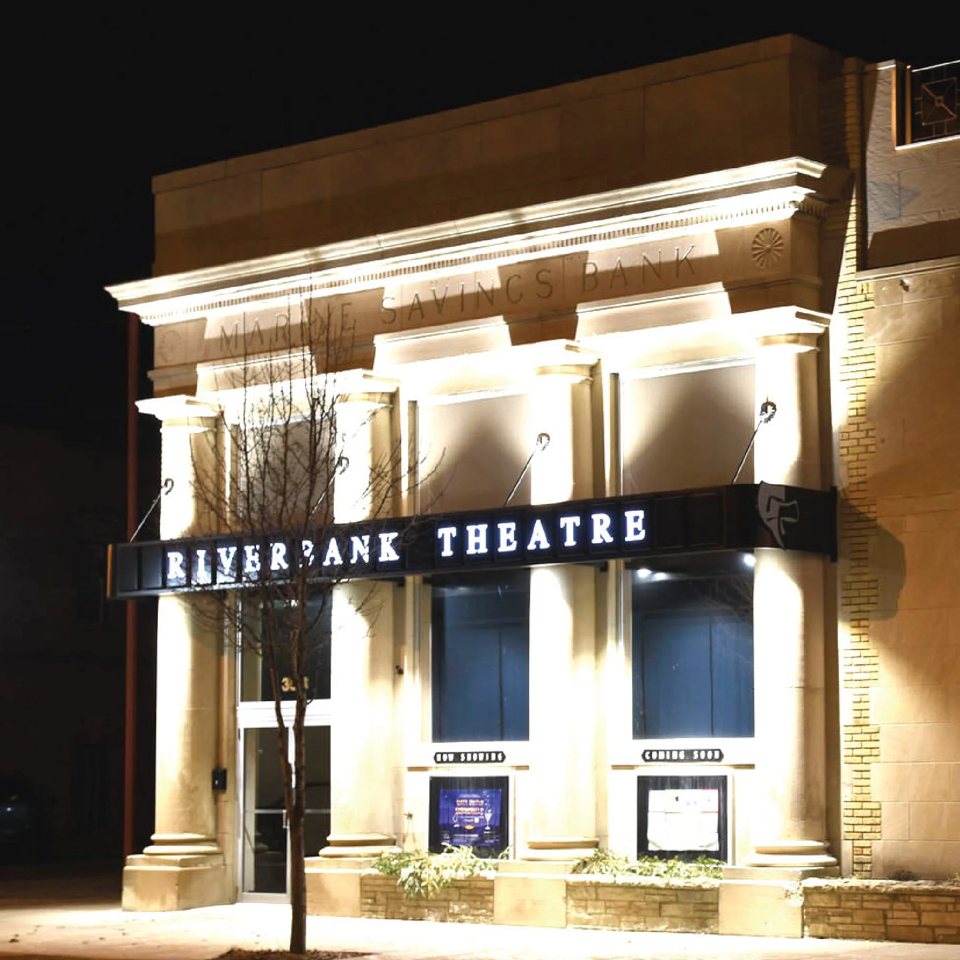 A Riverbank Theatre kivilágított, oszlopos homlokzata éjjel, az egykori Marine Savings Bank épületében