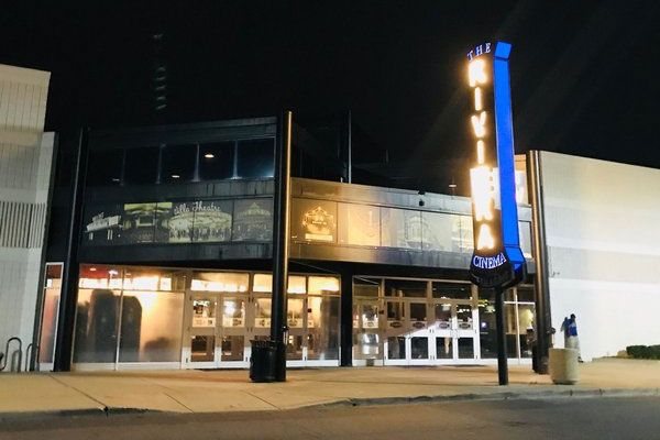 A mozi üvegportálos bejárata éjszaka, a kéken világító függőleges The Riviera Cinema felirattal