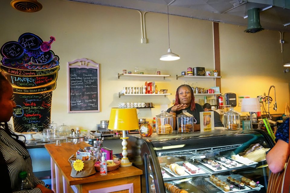 Inside a bakery and ice cream shop, the clerk chats with customers behind the counter