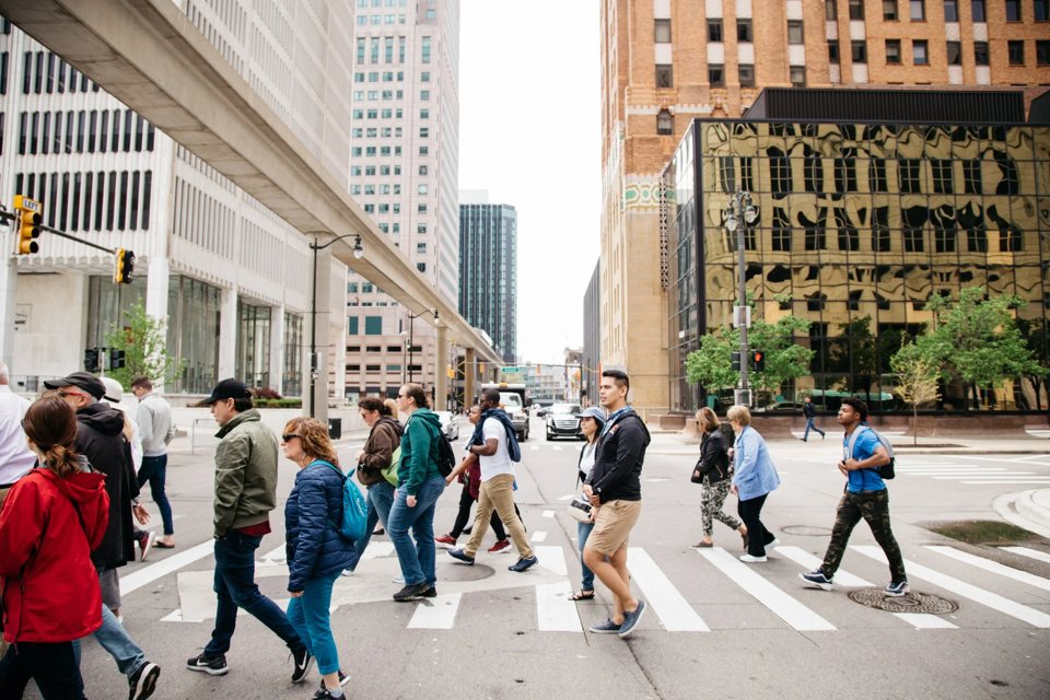 A túracsoport átkel az úttesten Detroit belvárosában, fent a People Mover sínjével