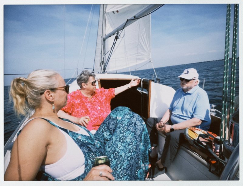 Passengers chat and relax on the sailboat's deck