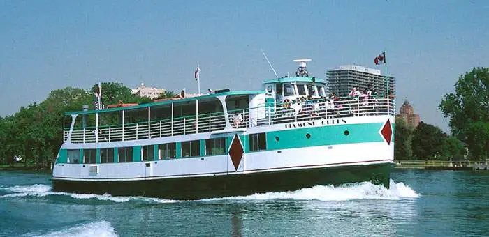 The green-and-white tour boat from the side, with passengers on deck
