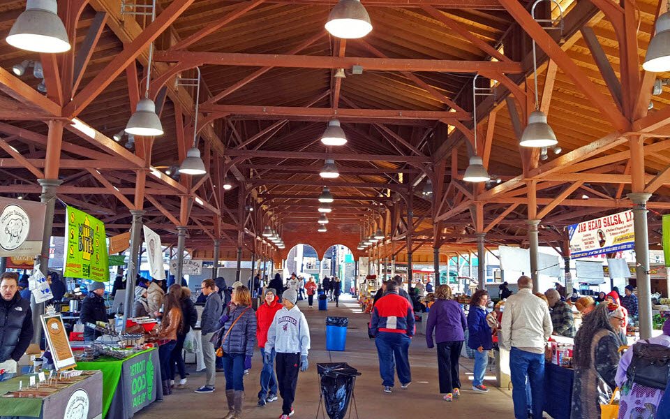 A crowded market shed interior with wooden beams, vendors, and shoppers at Eastern Market