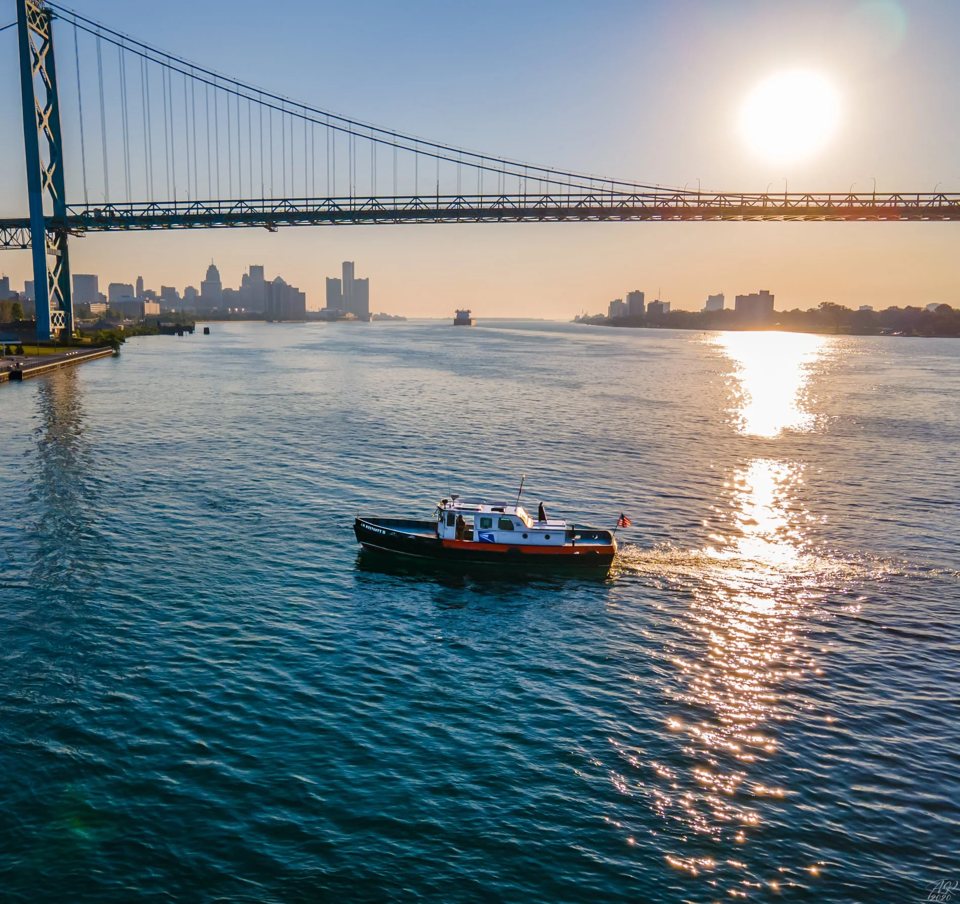 Sunset over the Detroit River with a boat, seen from aboard another vessel