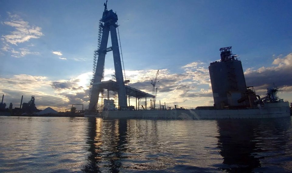 The Gordie Howe Bridge tower under construction, viewed from the river at dusk