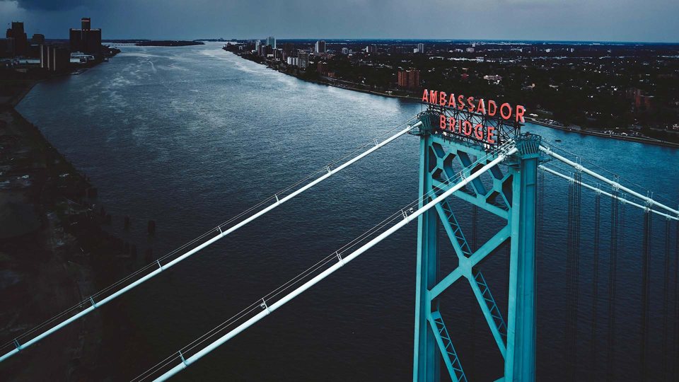 Aerial view of the Ambassador Bridge tower with the Detroit River and skyline below