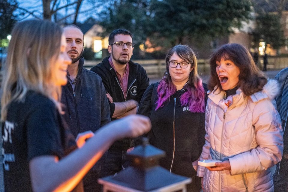 A ghost tour group listens to their guide at a mysterious Detroit location in evening light