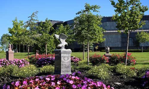 A historic statue stands among the cemetery's gravestones surrounded by flowers