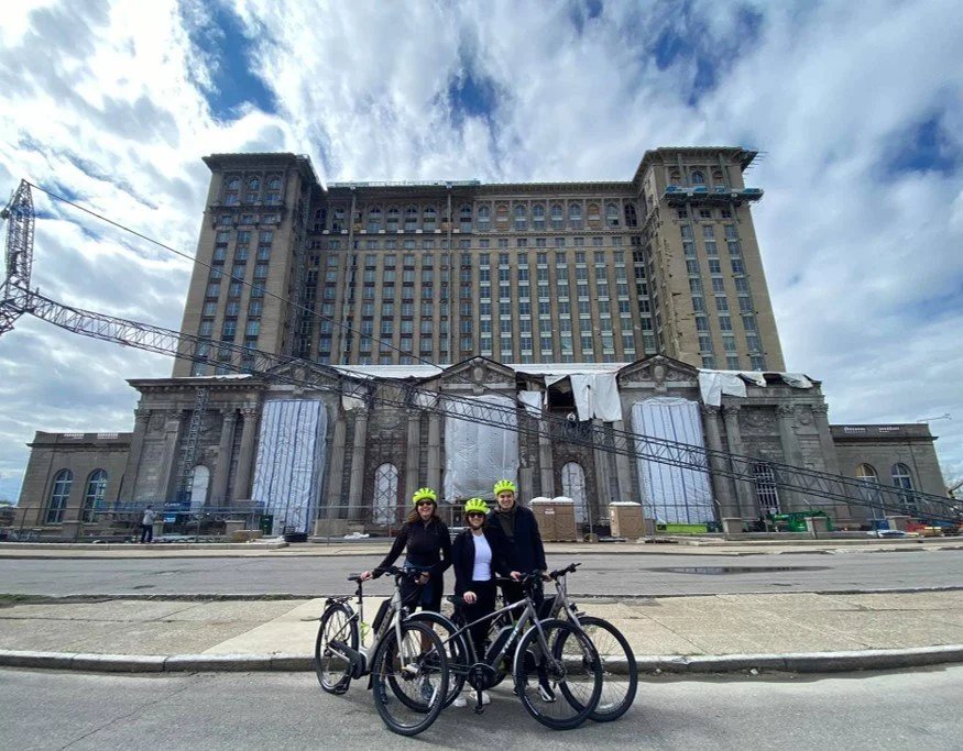 Két kerékpáros sziluettje a Michigan Central pályaudvar előtt naplementekor