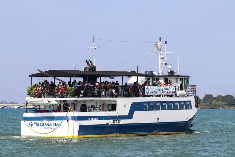 A boat full of passengers glides along the river during the day